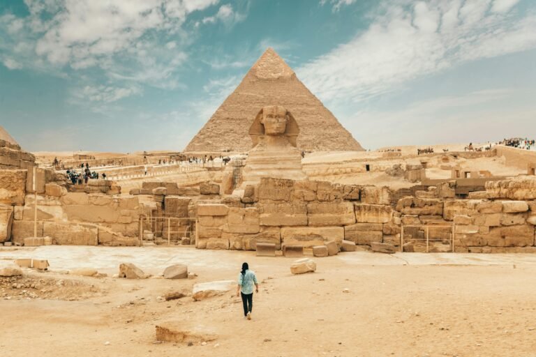 Back view of unrecognizable man walking towards ancient monument Great Sphinx of Giza