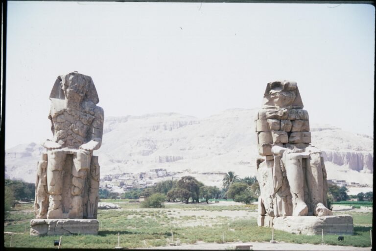 View of the Colossi of Memnon statues in Luxor, Egypt highlighting ancient Egyptian architecture.