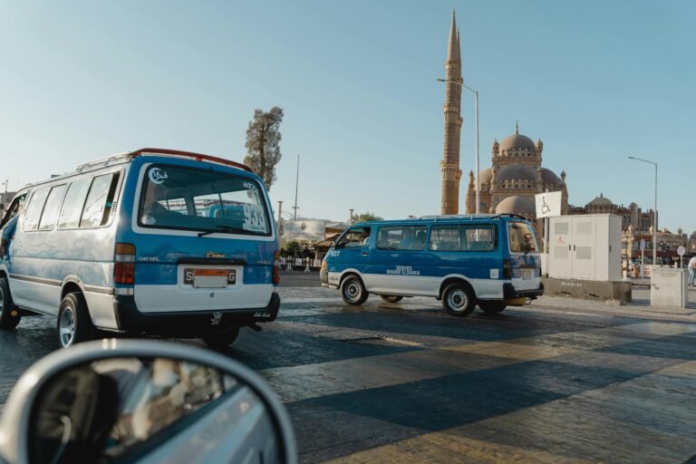 View of a city street featuring a mosque and parked minivans under clear skies.