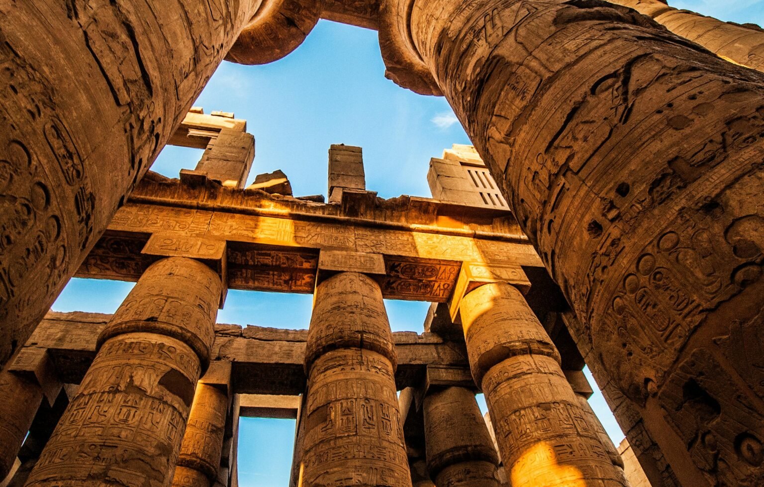 View of the majestic ancient columns in Karnak Temple, Egypt, under a clear sky.