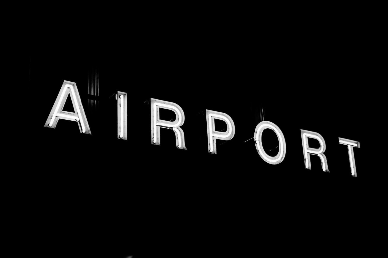 Illuminated neon airport sign glowing in the dark, minimal design.